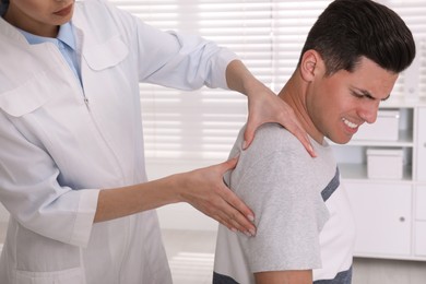 Doctor examining man with shoulder pain in hospital