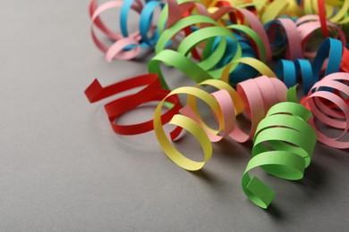 Photo of Colorful serpentine streamers on grey background. Space for text