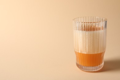 Glass of delicious eggnog on beige background. Space for text