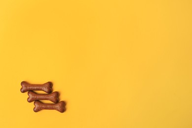Bone shaped dog cookies on orange background, flat lay. Space for text