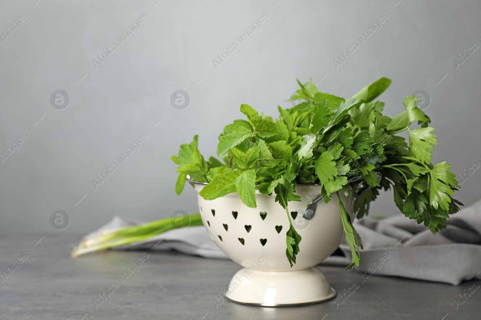 Photo of Colander with fresh parsley and mint on table