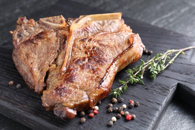 Photo of Delicious fried beef meat, thyme and peppercorns on table, closeup