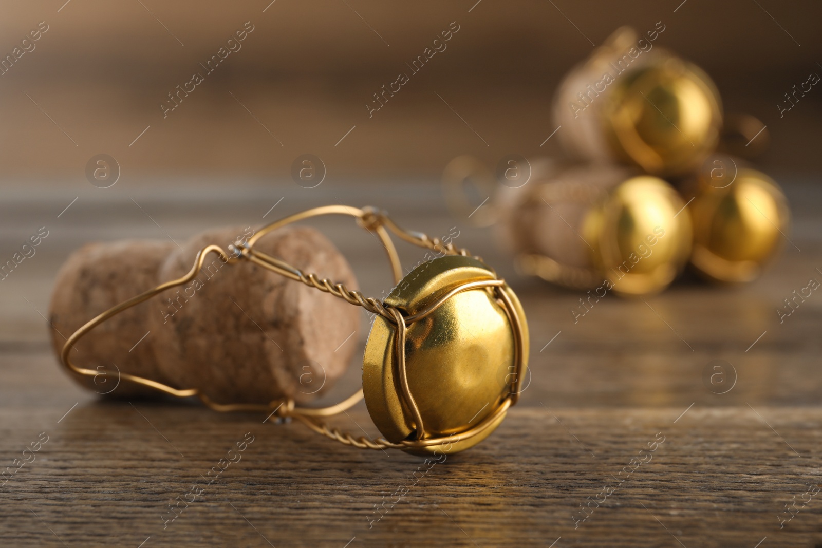 Photo of Cork of sparkling wine and muselet cap on wooden table, closeup. Space for text