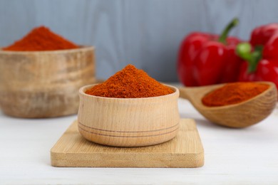 Bowls and spoon with aromatic paprika powder on white table