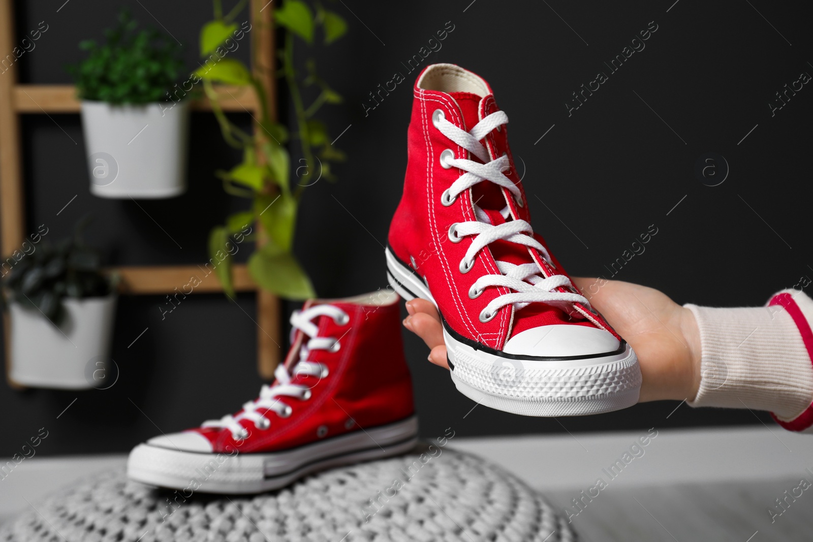 Photo of Woman with new stylish red sneakers indoors, closeup