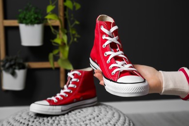 Photo of Woman with new stylish red sneakers indoors, closeup