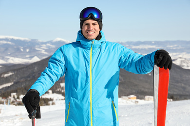 Photo of Happy man with ski equipment in mountains. Winter vacation