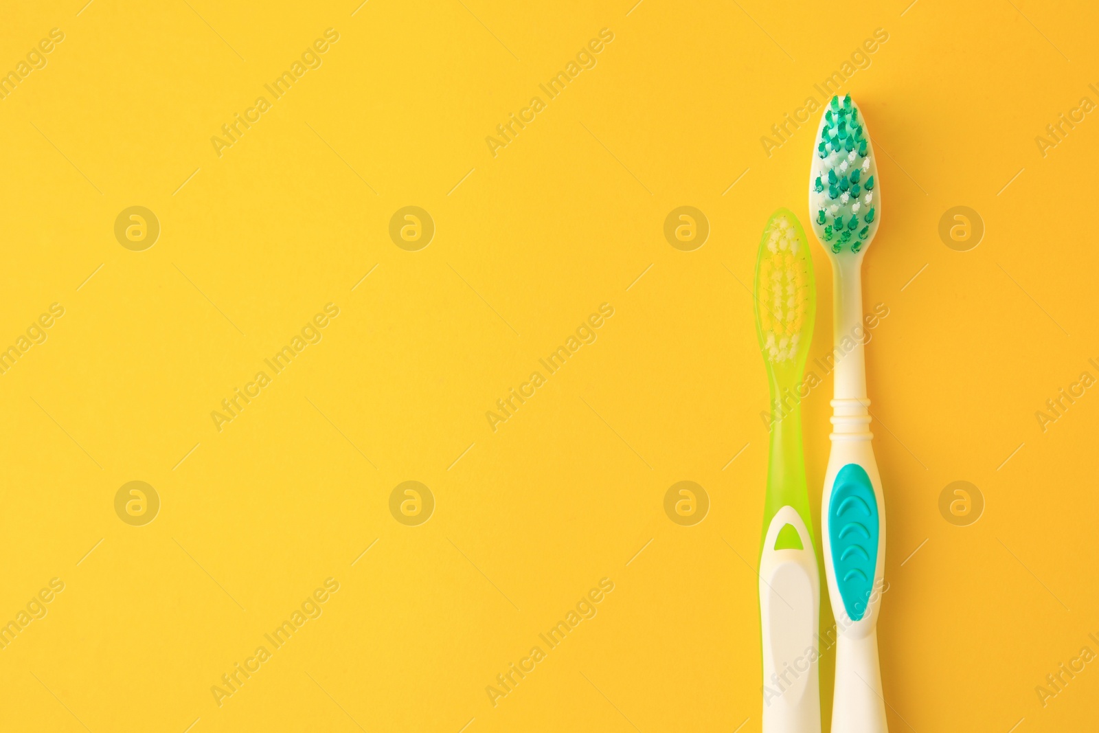 Photo of Toothbrushes on yellow background, flat lay. Space for text