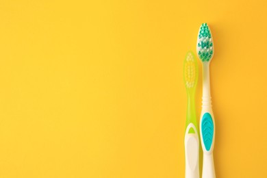 Photo of Toothbrushes on yellow background, flat lay. Space for text