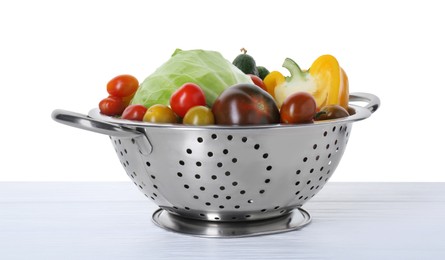 Photo of Metal colander with different vegetables on table against white background