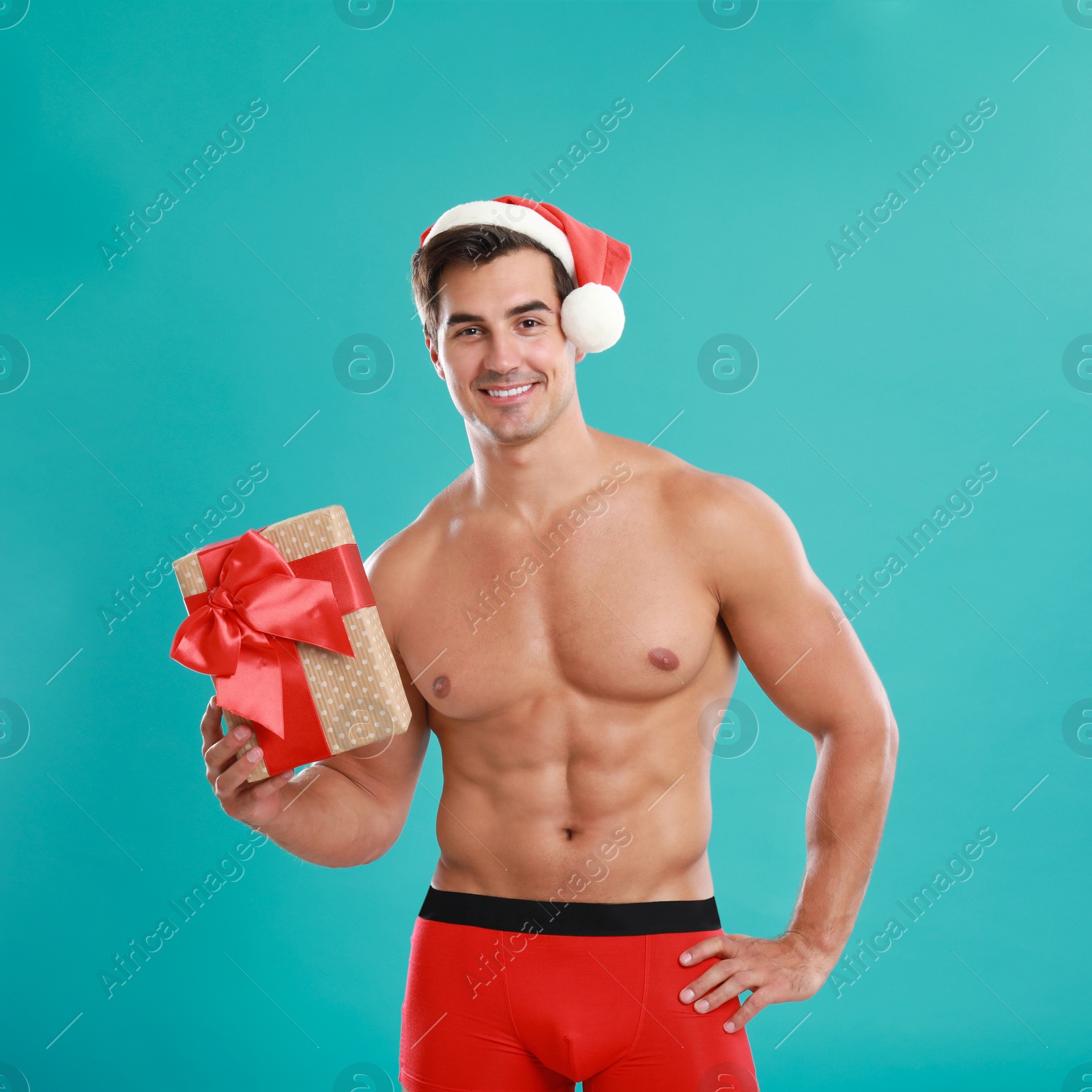 Photo of Sexy shirtless Santa Claus with gift on blue background