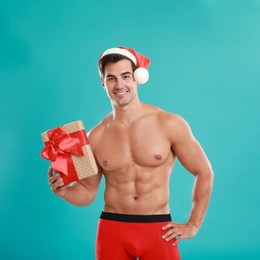 Photo of Sexy shirtless Santa Claus with gift on blue background