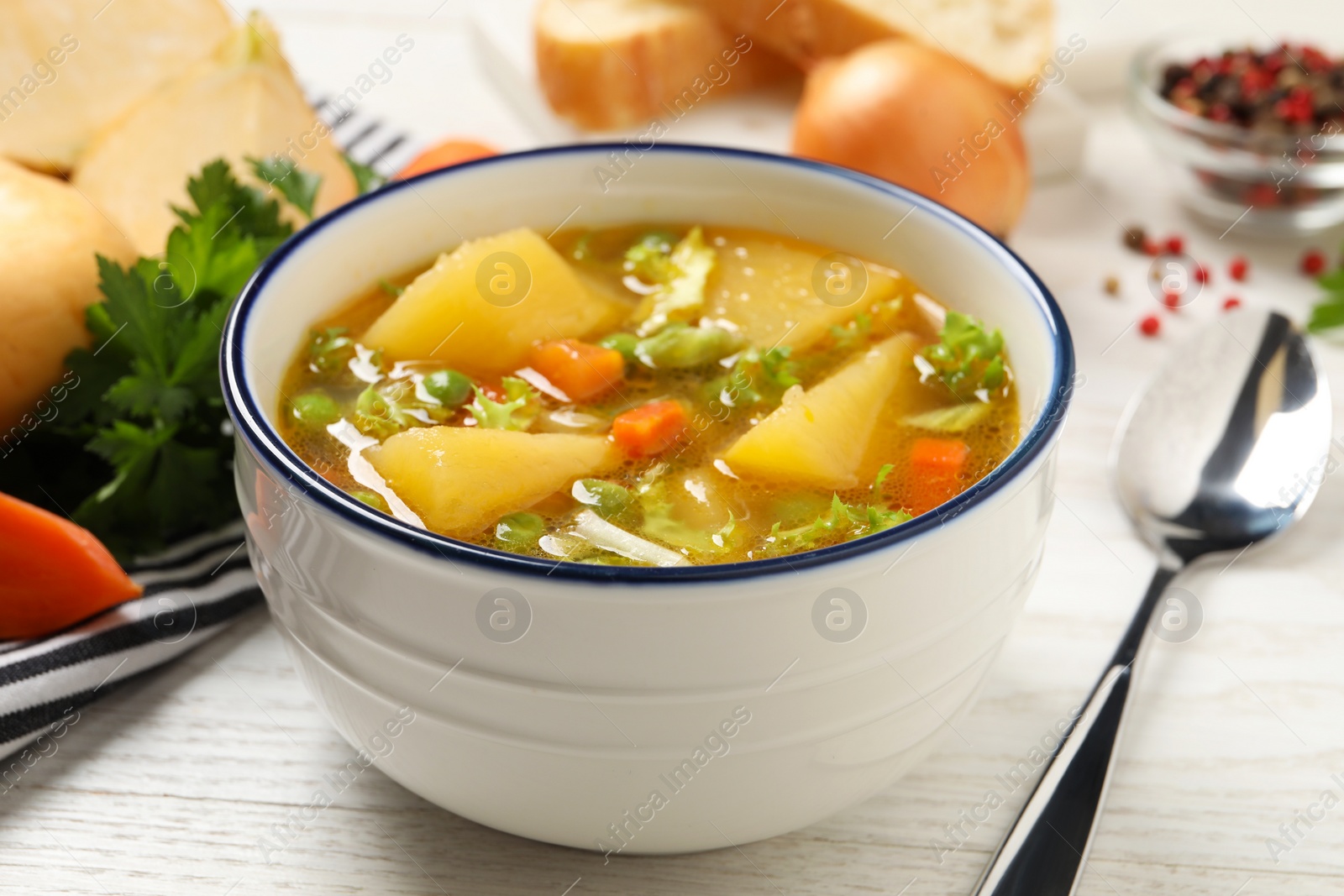 Photo of Bowl of delicious turnip soup served on white wooden table, closeup