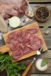 Photo of Board with slices of raw beef tongue and products on wooden table, flat lay