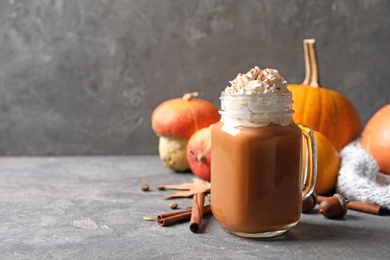 Photo of Mason jar with tasty pumpkin spice latte on gray table. Space for text