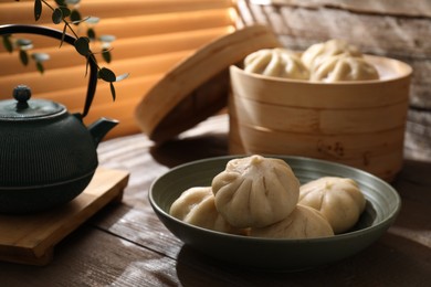 Delicious bao buns (baozi) in bowl on wooden table, closeup