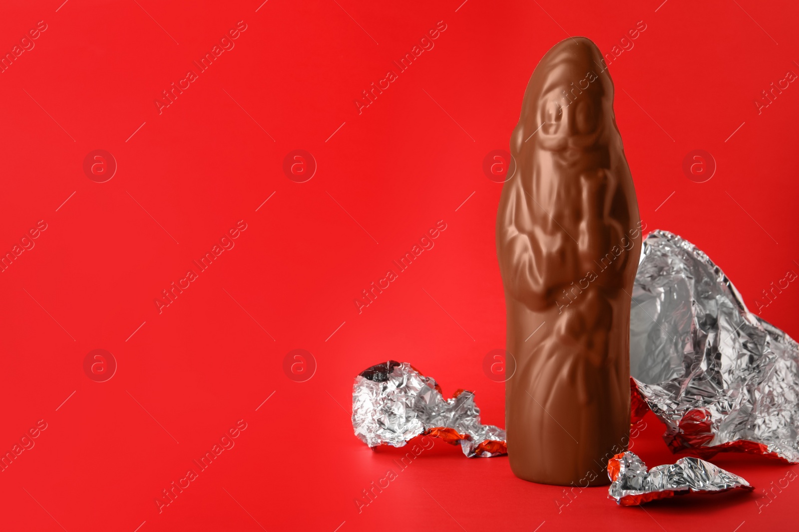 Photo of Unwrapped chocolate Santa Claus on red background. Space for text