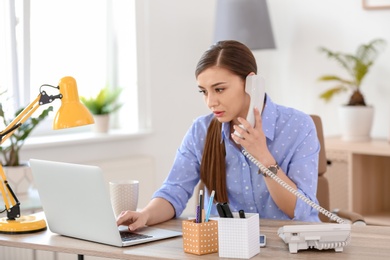 Young woman talking on phone at workplace