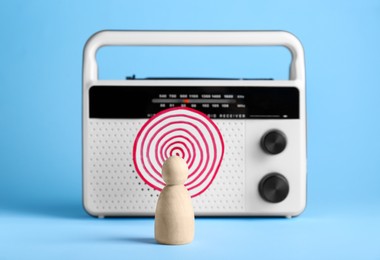 Photo of Propaganda concept. Human mired in media field. Wooden figure in front of radio with hypnotizing paper circle