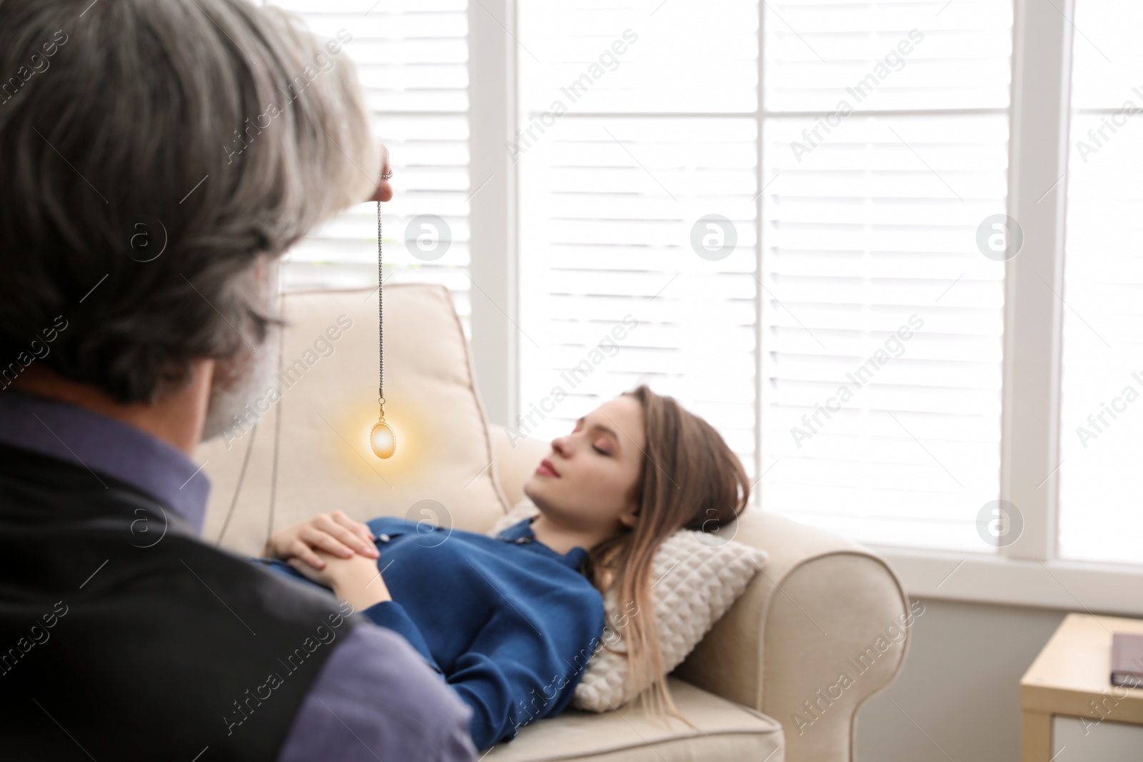 Photo of Psychotherapist using pendulum during hypnotherapy   session in office