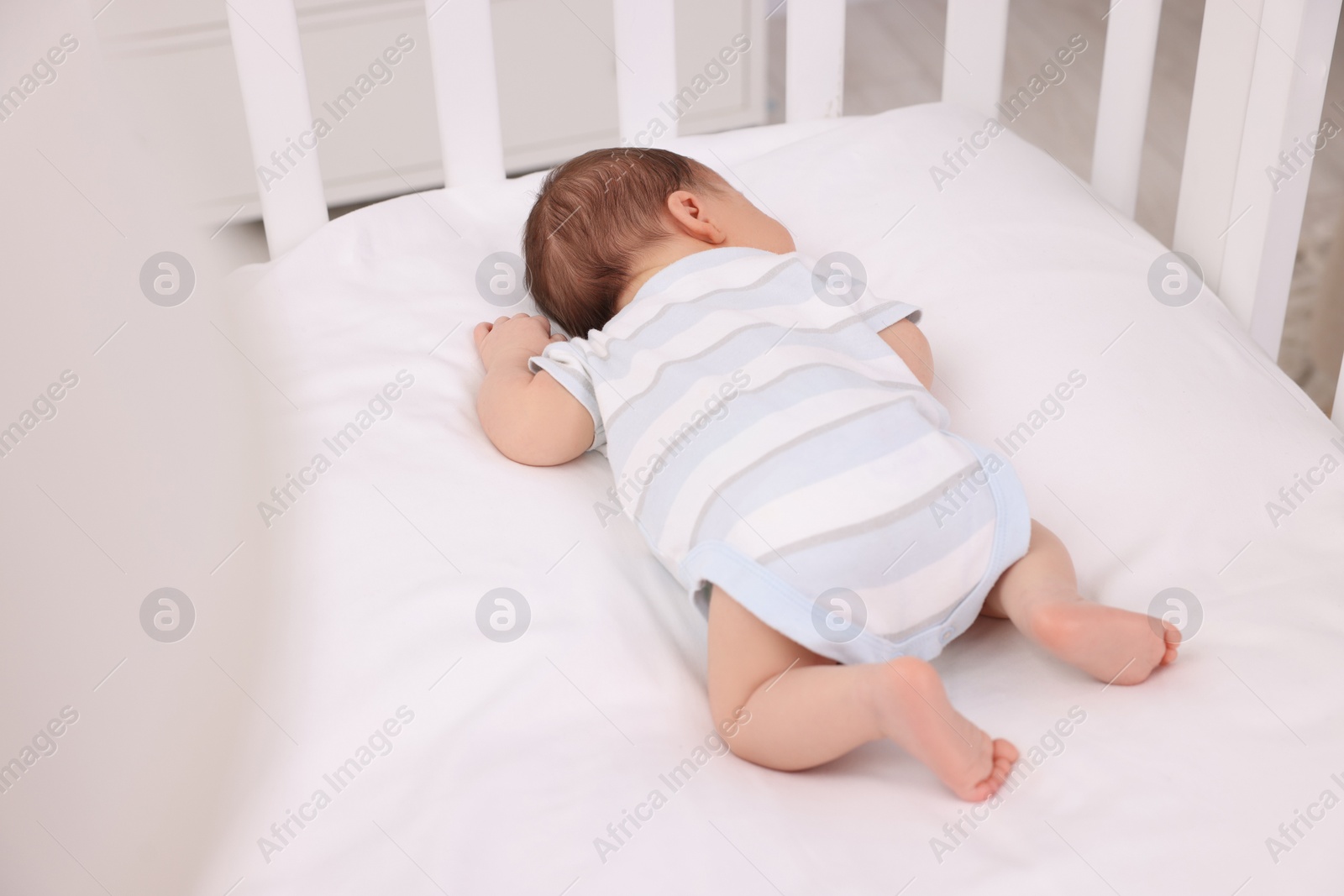 Photo of Cute newborn baby sleeping in crib. Bedtime