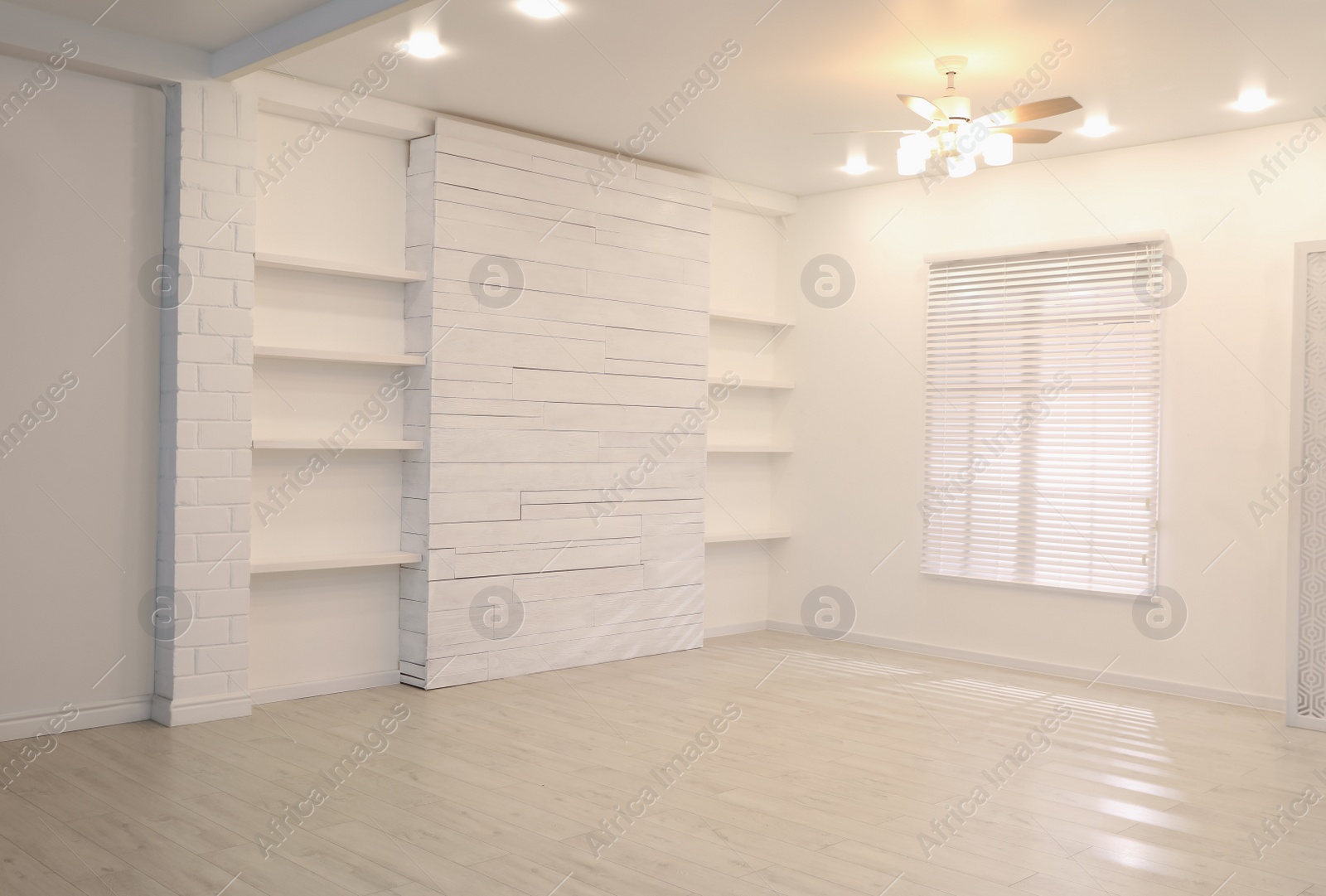 Photo of Empty room with textured wall, stylish wooden shelves and large window