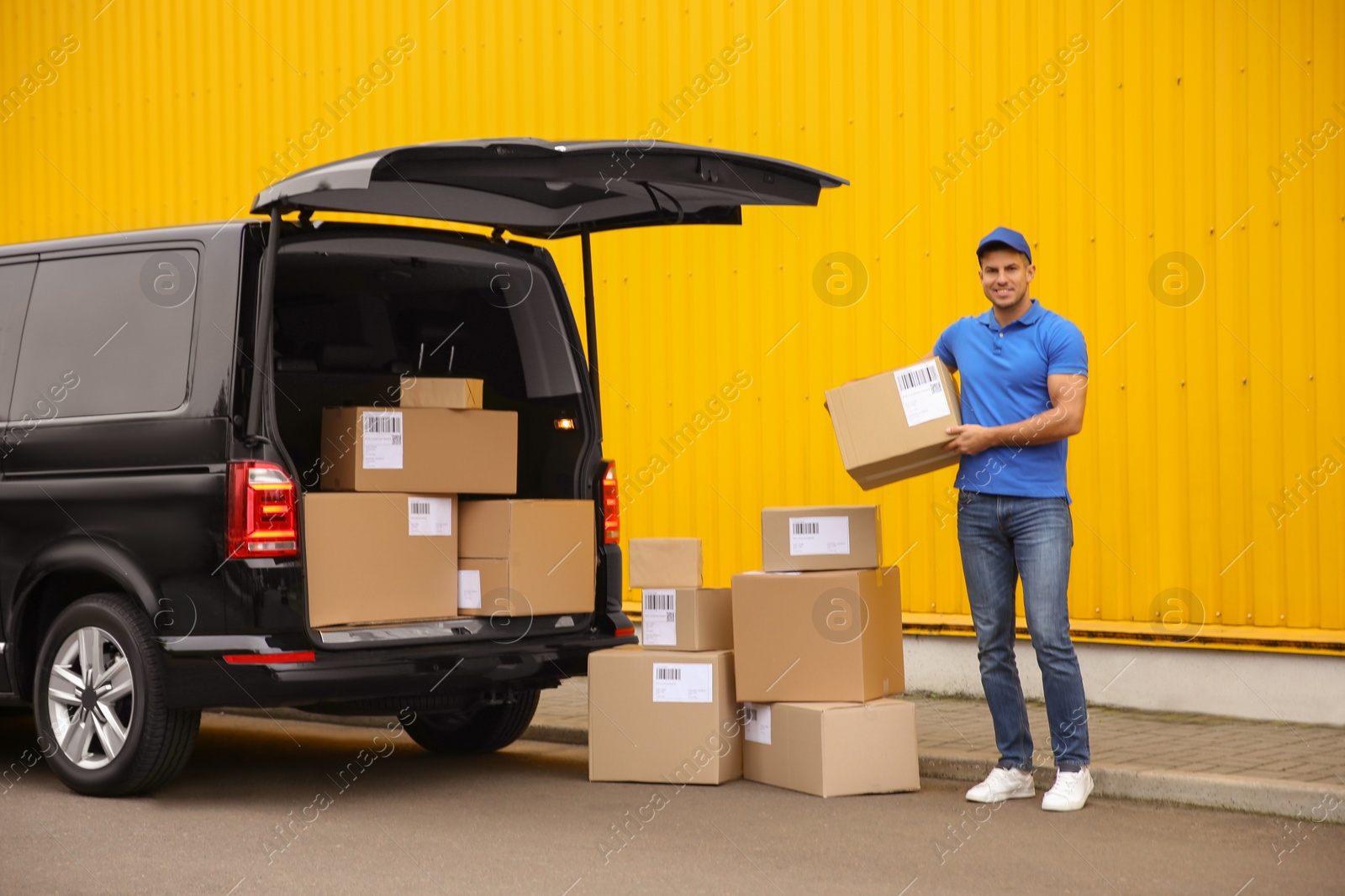 Photo of Courier with parcels near delivery van outdoors