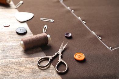 Photo of Set of tailoring accessories and fabric on wooden background