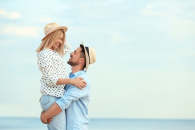 Happy romantic couple spending time together on beach, space for text