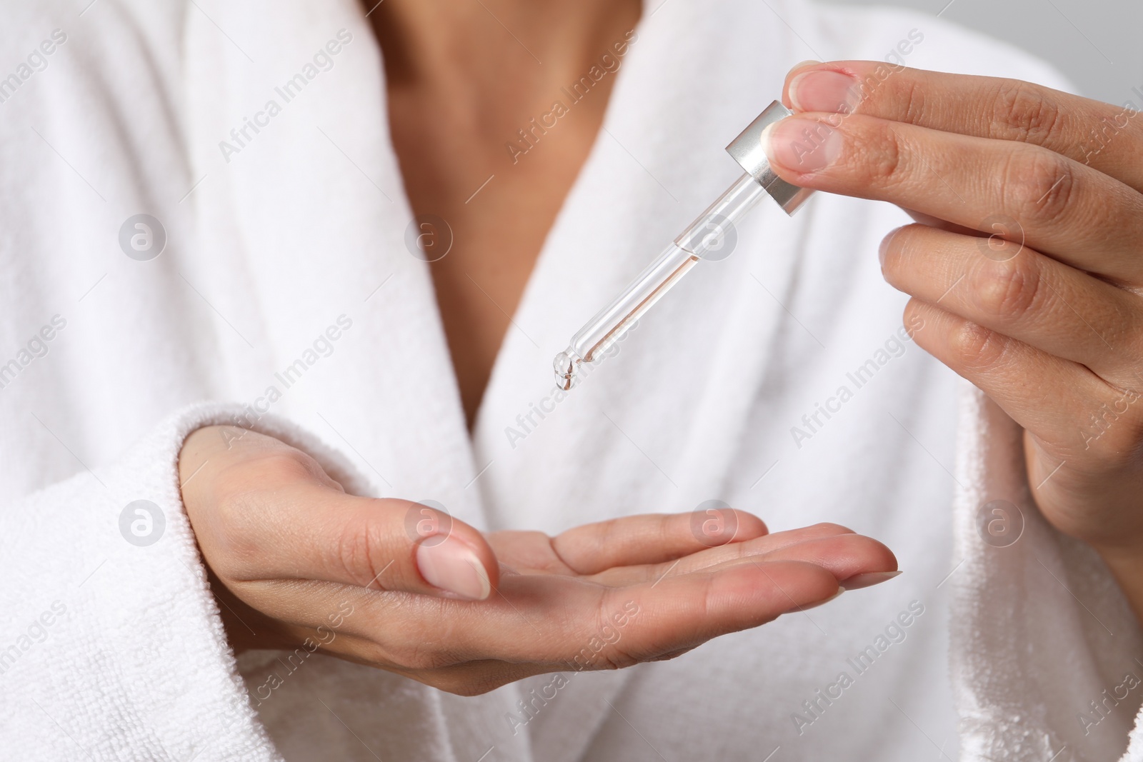 Photo of Woman applying cosmetic serum onto her hand, closeup