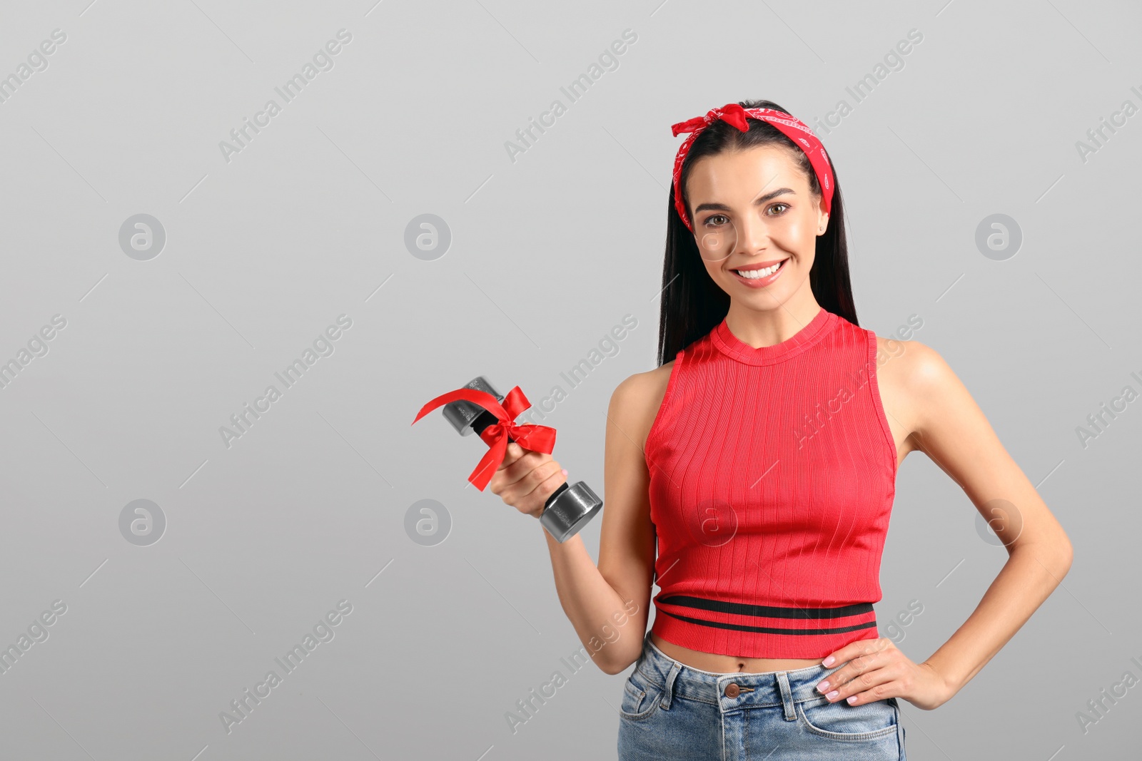 Photo of Woman with dumbbell as symbol of girl power on light grey background, space for text. 8 March concept