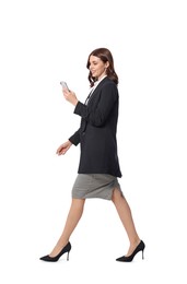 Photo of Happy young woman in formal suit using smartphone while walking on white background