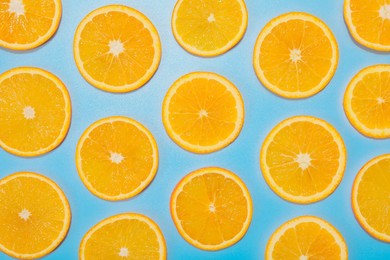 Photo of Slices of juicy orange on light blue background, flat lay