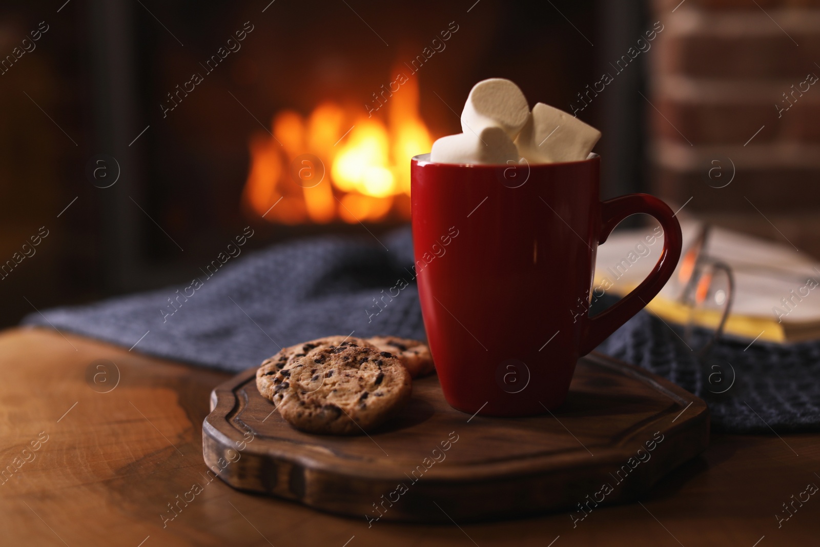 Photo of Delicious sweet cocoa with marshmallows, cookies and blurred fireplace on background