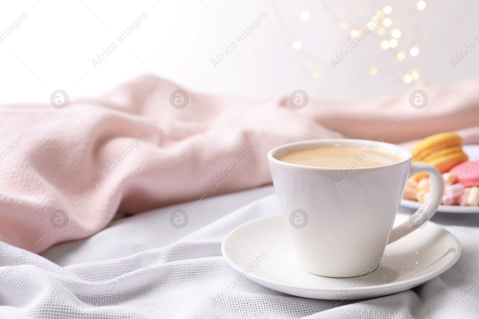 Photo of Cup of hot coffee with dessert on light linens, space for text