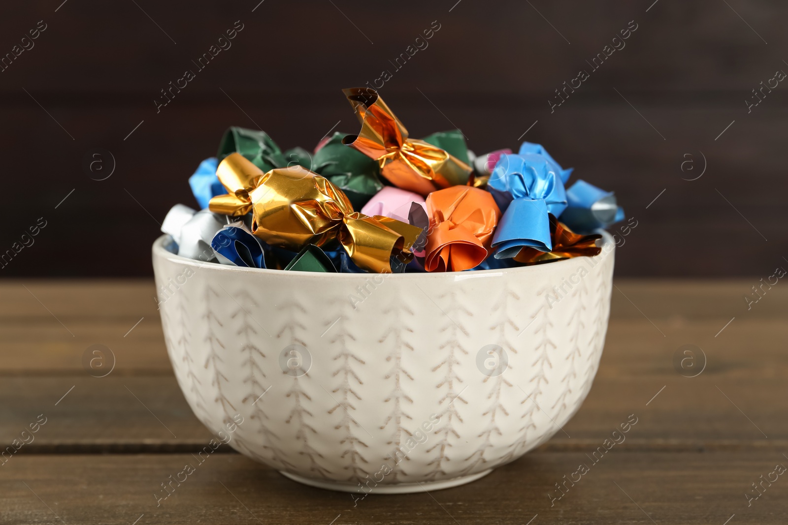 Photo of Candies in colorful wrappers on wooden table, closeup