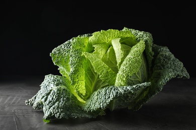 Fresh green savoy cabbage on grey table against black background