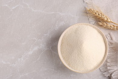 Photo of Uncooked organic semolina and spikelets on light table, flat lay. Space for text