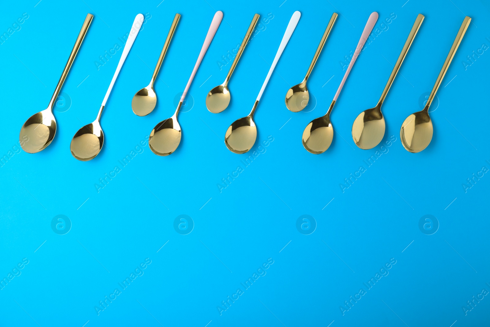 Photo of New gold spoons on blue background, flat lay with space for text