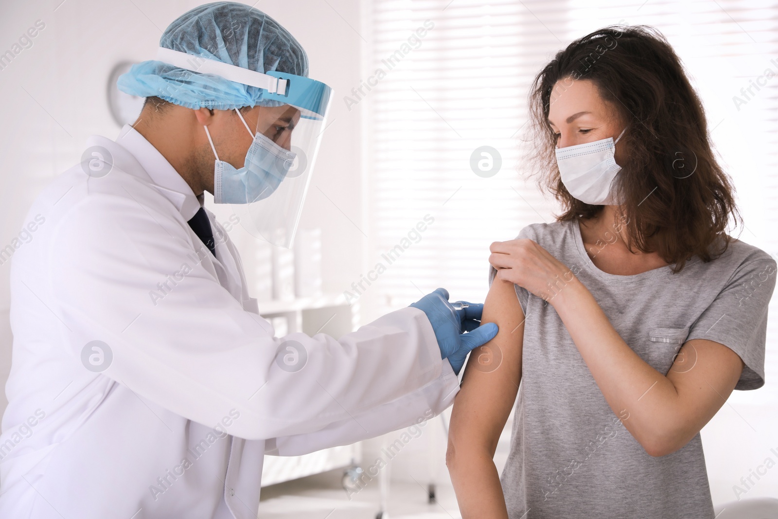 Photo of Doctor vaccinating mature woman against Covid-19 in clinic