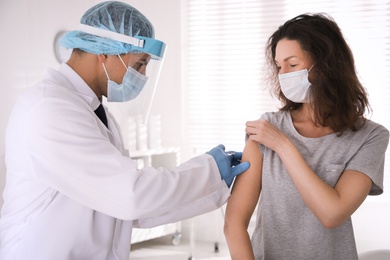 Doctor vaccinating mature woman against Covid-19 in clinic