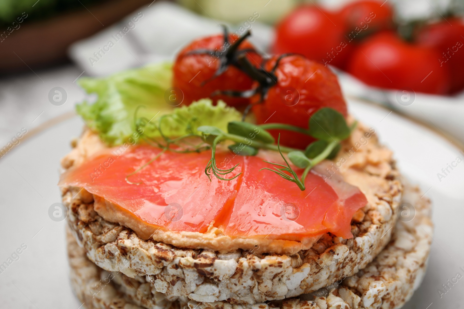 Photo of Crunchy buckwheat cakes with salmon, tomatoes and greens on plate, closeup