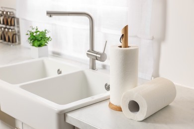 Photo of Rolls of paper towels on white countertop in kitchen, space for text