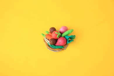 Photo of Different plasticine vegetables on yellow background. Children's handmade ideas