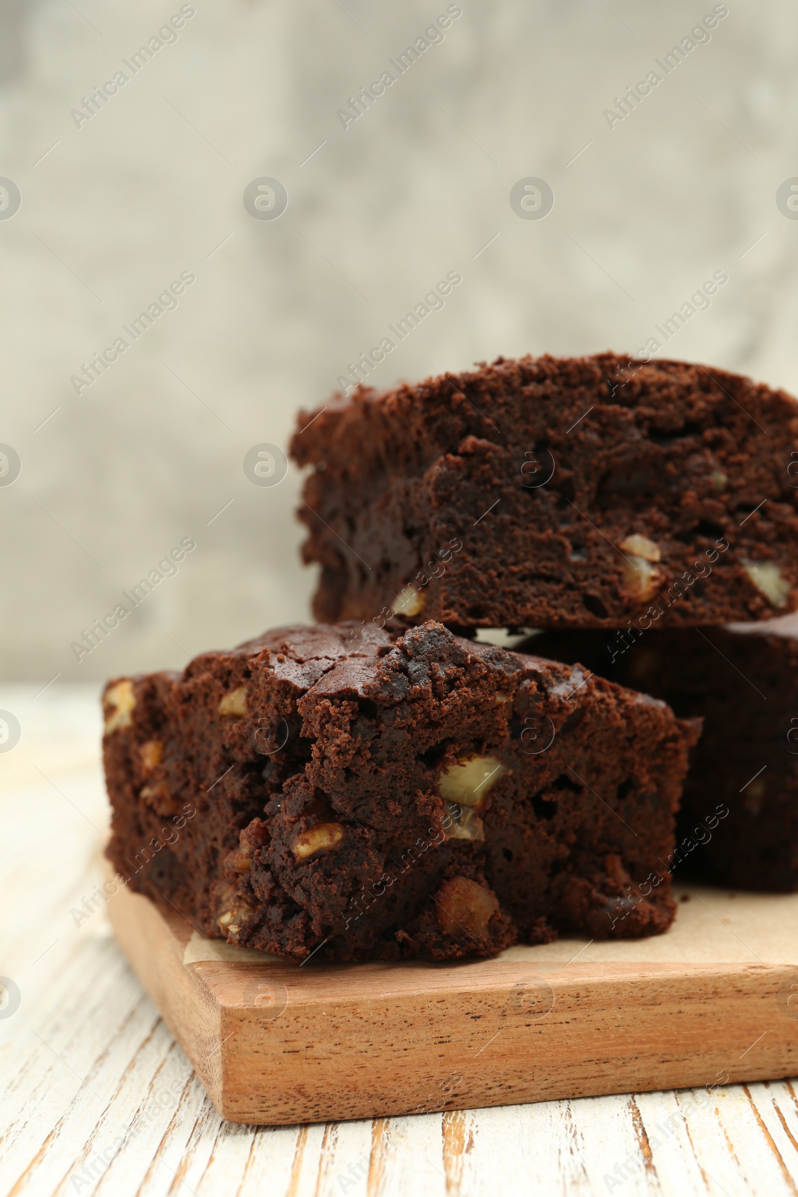 Photo of Delicious brownies with nuts on white wooden table, closeup