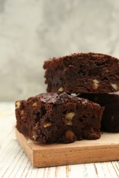 Delicious brownies with nuts on white wooden table, closeup
