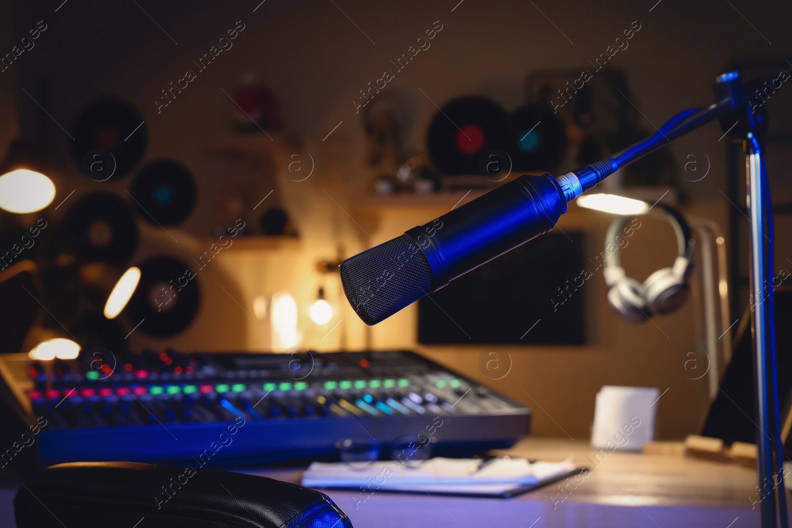 Photo of Microphone near table with professional mixing console in radio studio