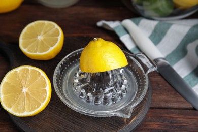 Photo of Glass squeezer and fresh lemons on wooden table