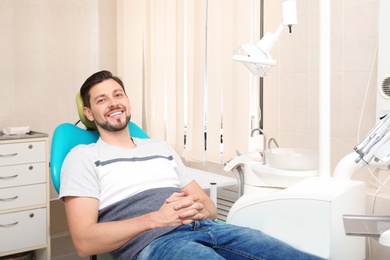 Photo of Happy man having dentist's appointment in modern clinic. Space for text