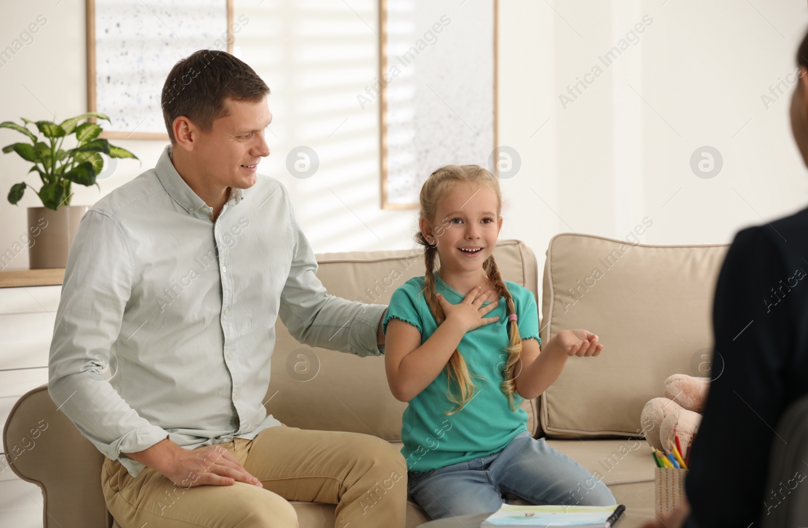 Photo of Little girl and her father on appointment with child psychotherapist indoors